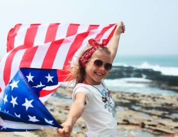 A young girl on the beach with an American flag