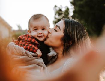 mother kissing baby's cheek