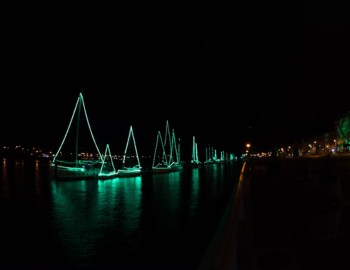 estively decorated boats illuminated at dusk during the Holiday Parade of Boats along Charleston Harbor, South Carolina.