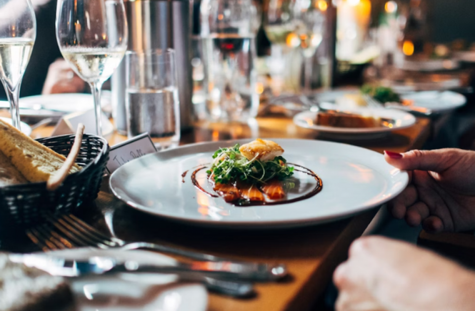 Guests dining in a warm, stylish Charleston restaurant with beautifully plated dishes during Restaurant Week