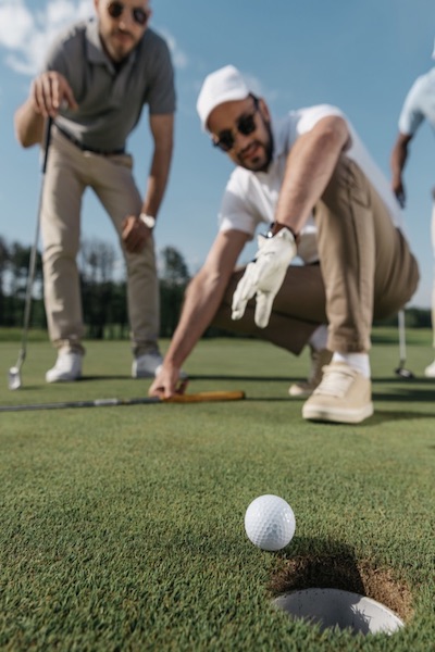 A group of men watch a putt