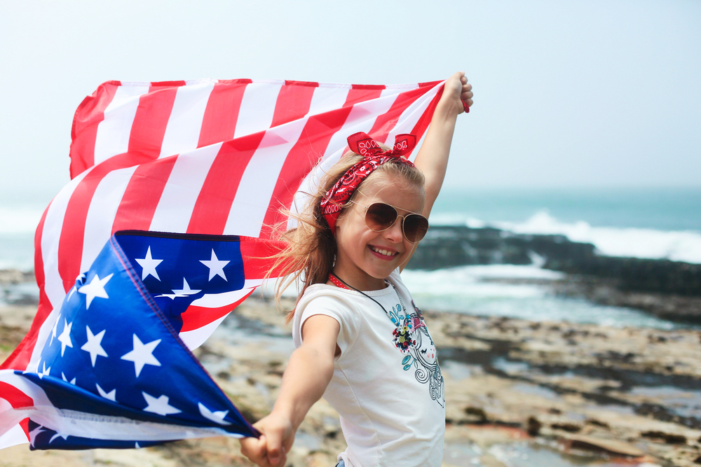 A young girl on the beach with an American flag