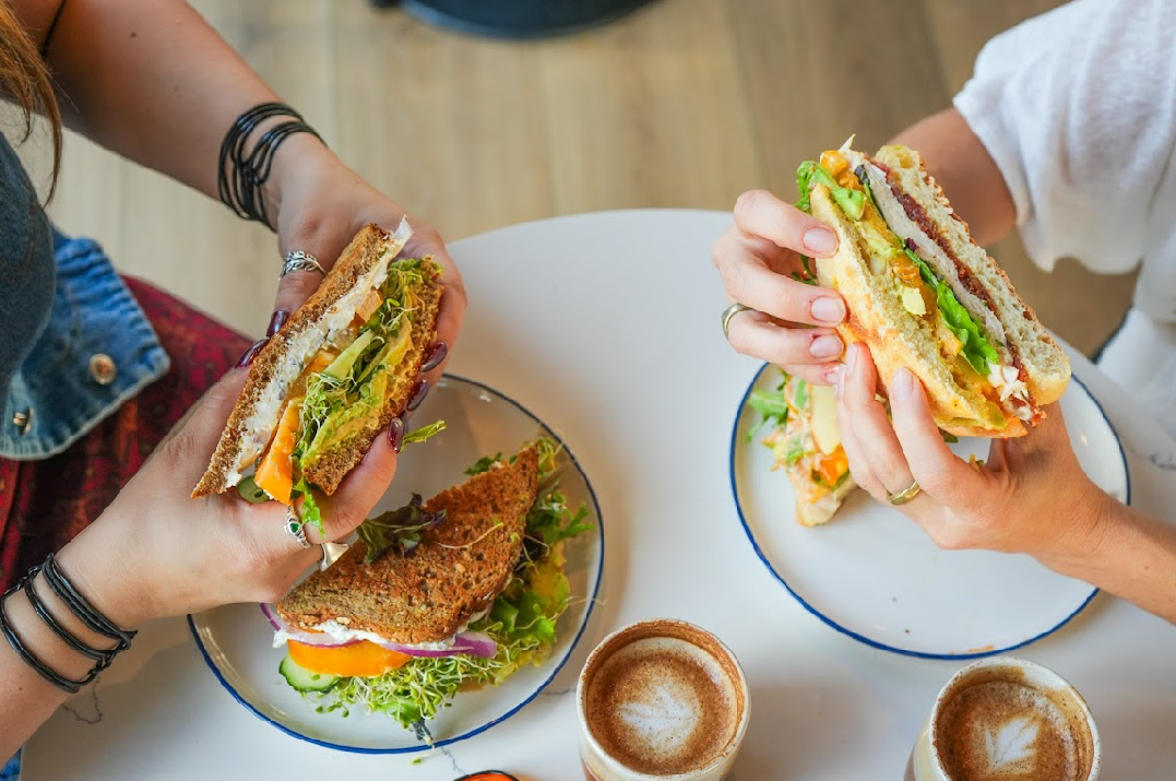 women eating sandwiches in cafe